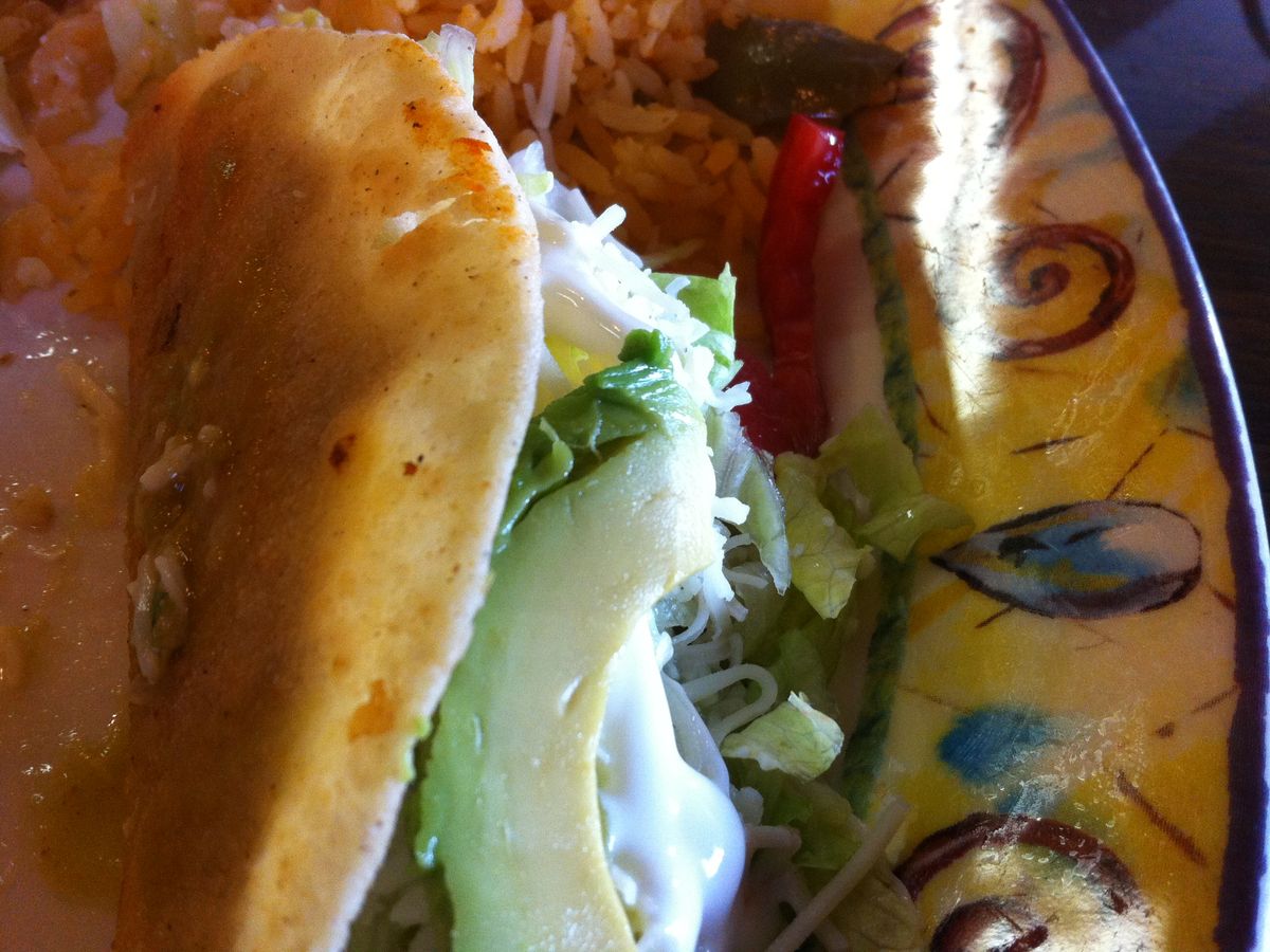 A taco with rice on a painted plate